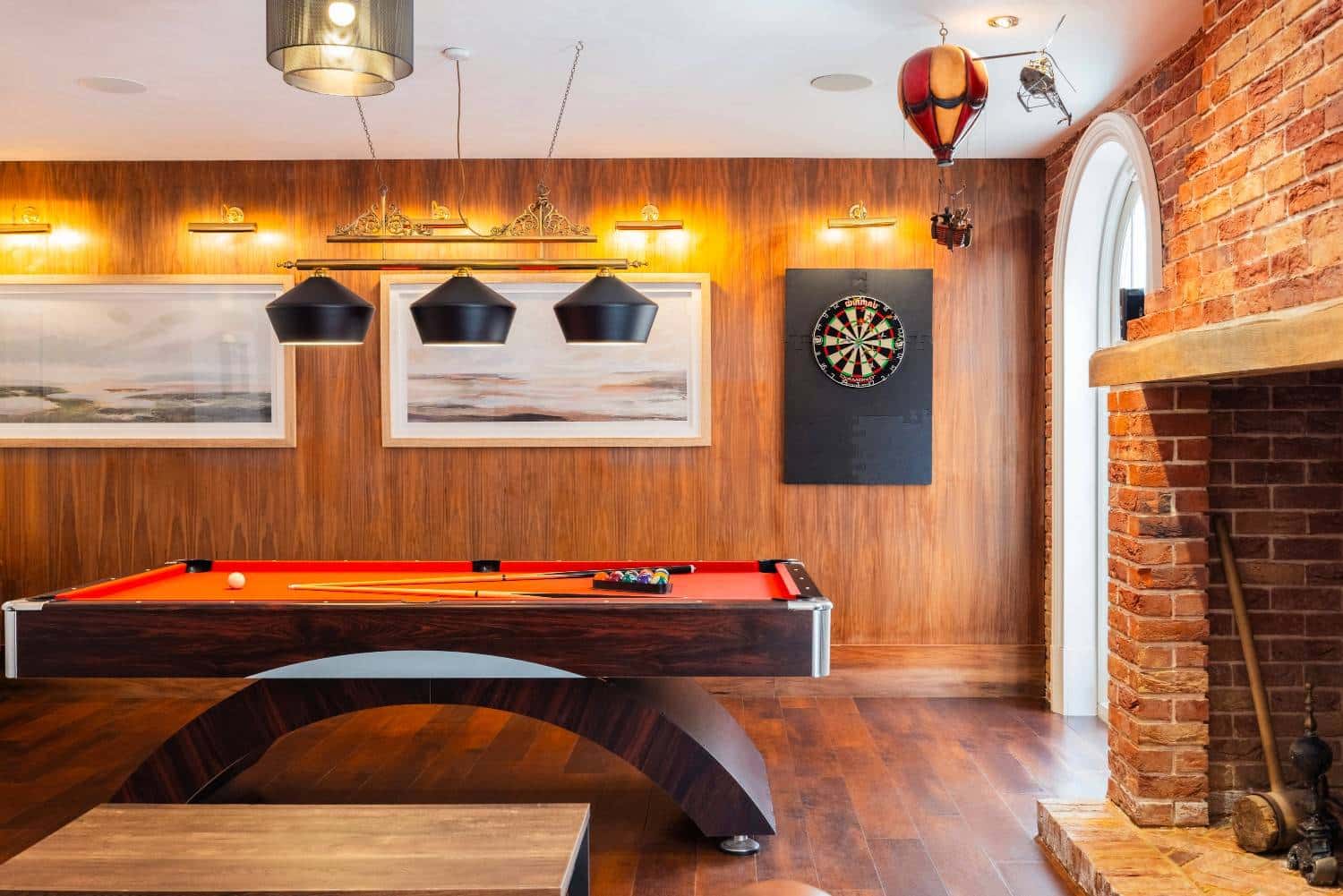 view of a red pool table with a dart board behind it at one of our Party Houses with a game room